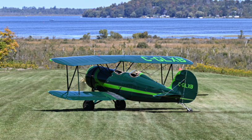 Photo of an airplane on a grass airstrip overlooking Lake Scugog.